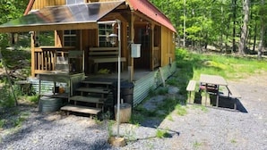 A rustic cabin with a sloped roof, a front porch, and a small outdoor seating area.