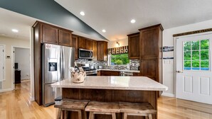 Une cuisine moderne avec des meubles en bois, des appareils électroménagers en acier inoxydable et un grand îlot central doté de tabourets.