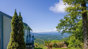 Une cabane offrant une vue panoramique sur les montagnes, avec une clôture en bois et un banc.