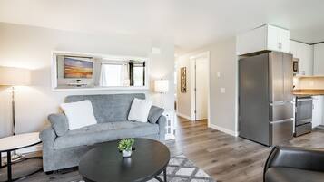 A modern living room with a grey sofa, a black coffee table, and a TV mounted above it.