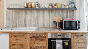 A kitchen with a wooden countertop, a sink, a microwave, and a built-in oven. - Rustic Revived Victorian Seaside Retreat (Bournemouth)