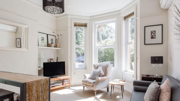 A modern living room with a television, a grey sofa, a wooden coffee table, and a chair. - Rustic Revived Victorian Seaside Retreat (Bournemouth)
