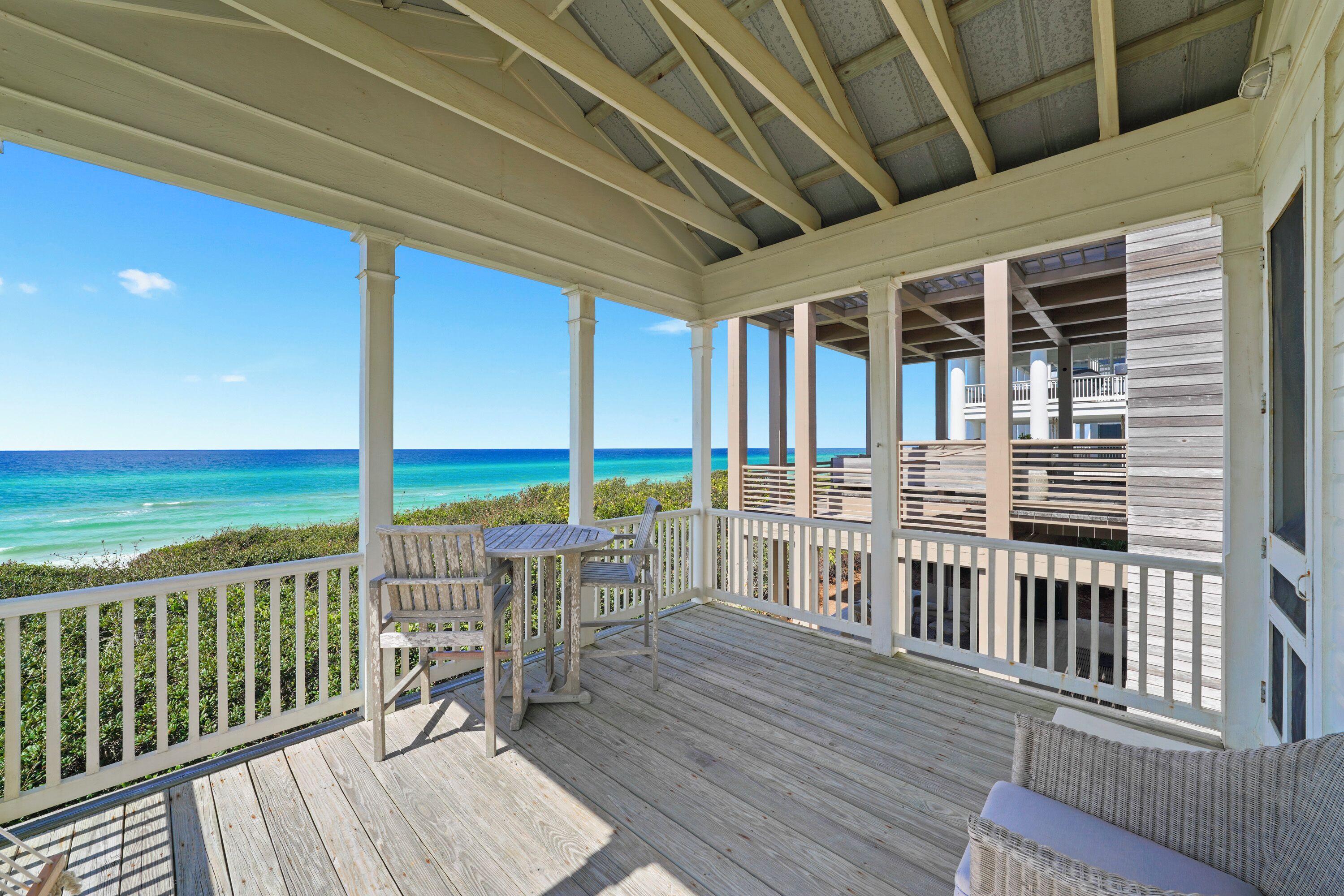 A covered outdoor area with a wooden deck, a table, and two chairs.