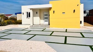 A modern two-story house with a yellow facade and a white entrance. - Aruba Personal Paradise-2BR Home w/ private pool, convenient location (Noord)