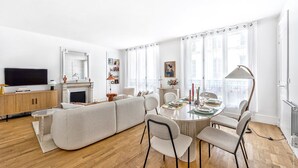 Een moderne woonkamer met een bank, eettafel, stoelen en een open haard.