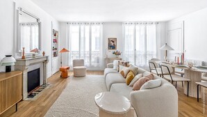 Een moderne woonkamer met een open haard, een zithoek, een eettafel en een keuken.