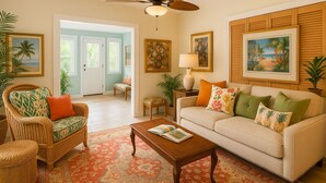 A living room with a sofa, coffee table, wicker chairs, and a patterned rug. - Historical botanical beach house (Lake Worth Beach)