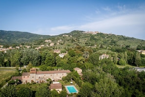 Une villa avec piscine, entourée d’une végétation luxuriante et de collines.