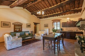 A spacious living area with a wooden ceiling, a dining table, and a kitchen area. - Villa Gelsi by MMega (Cortona)