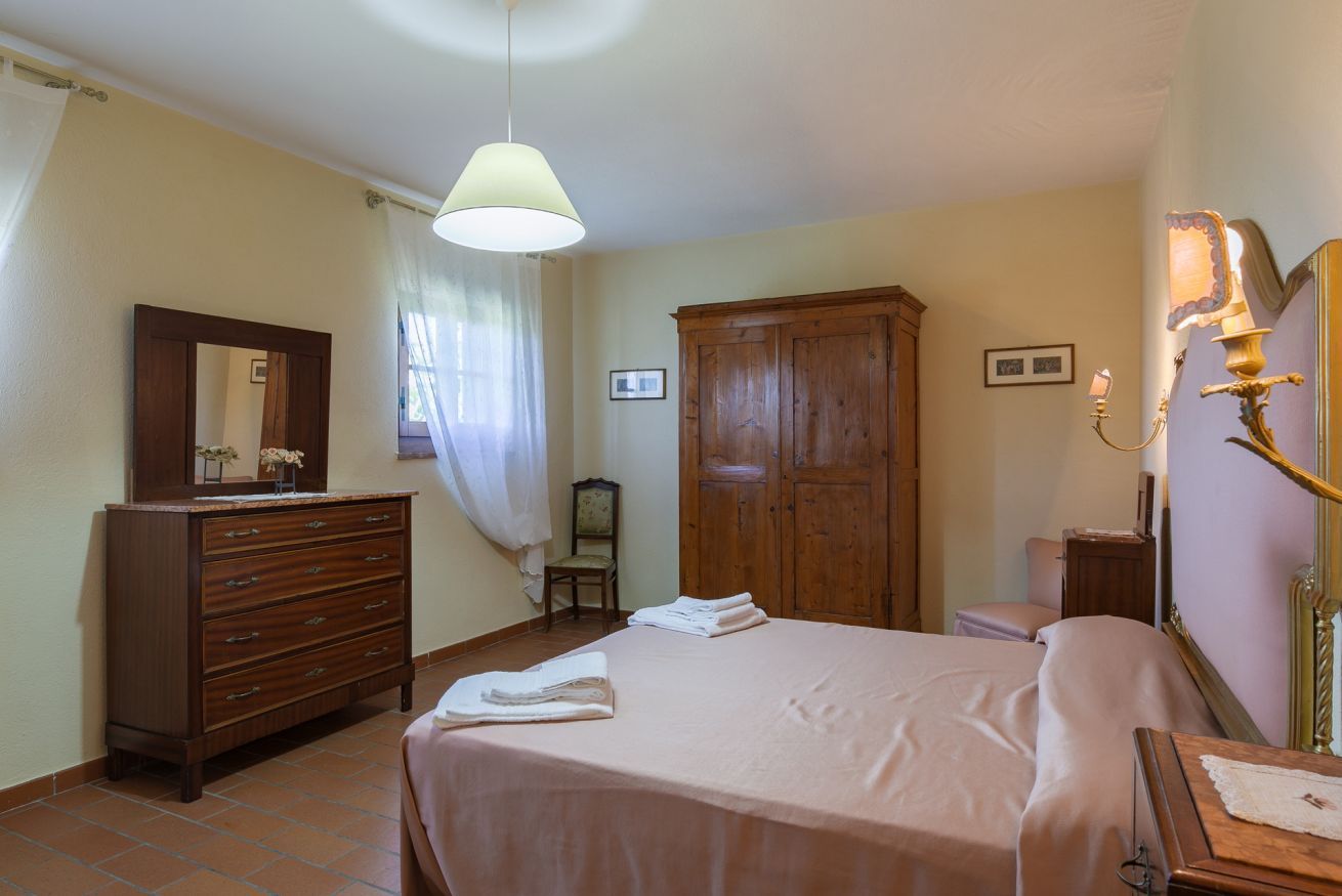 A bedroom with a bed, dresser, wardrobe, and a mirror.