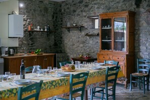 Un coin repas agrémenté d’un mur en pierre, de meubles en bois et d’une table dressée pour quatre personnes.