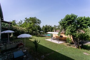 A backyard with a pool, outdoor furniture, and umbrellas.