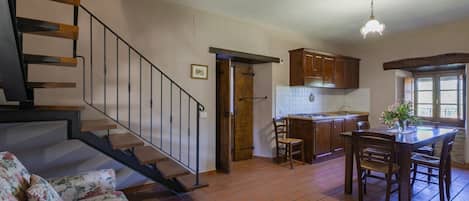 A kitchen with wooden cabinets, a dining table, and a staircase.
