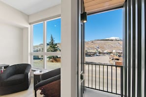 Una habitación con ventanas amplias, un balcón y vistas a un paisaje nevado.