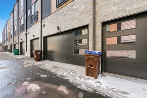 A row of modern buildings with garage doors, trash bins, and a clear sky.