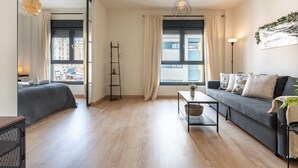 Un salon moderne avec un canapé gris, une petite table, un lampadaire et une fenêtre avec des rideaux.