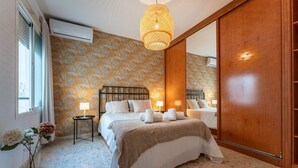 Une chambre à coucher avec un lit, des tables de chevet, un miroir et un vase de fleurs.