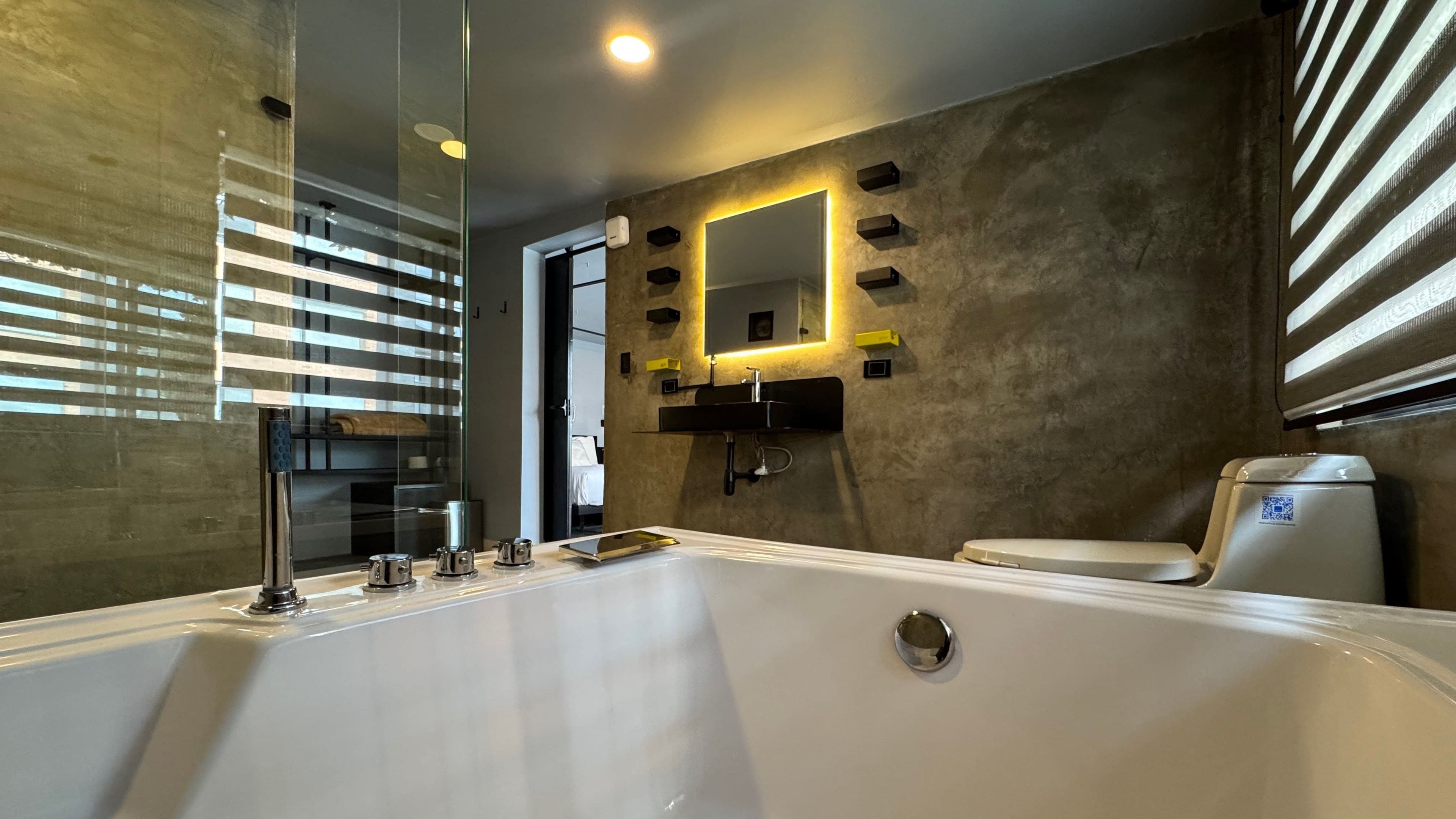 A modern bathroom with a large bathtub, a wall-mounted sink, and a toilet.