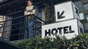 A hotel sign with a directional arrow and a person on a balcony. - Hostal Joy Calle 85 (Bogotá)