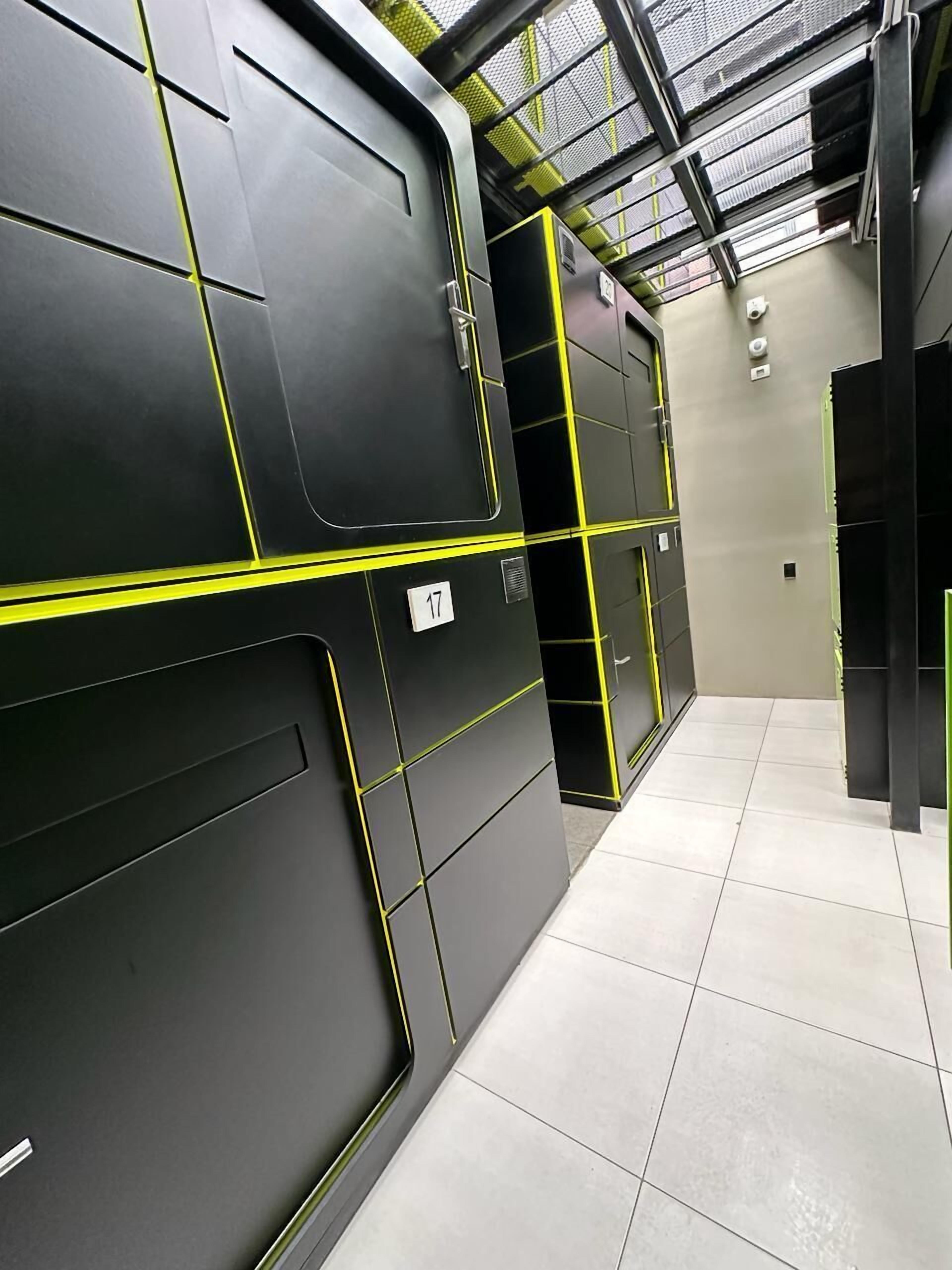 A modern, industrial-style room with black and yellow lockers, a tiled floor, and a high ceiling with skylights.