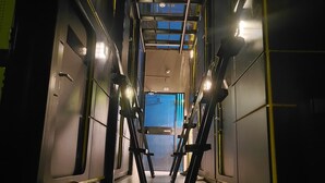 A corridor with a high ceiling, metal railings, and a view of a blue sky through a skylight. - Hostal Joy Calle 85 (Bogotá)
