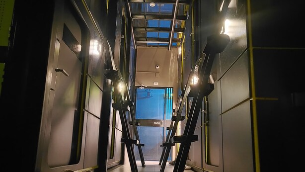 A corridor with a high ceiling, metal railings, and a view of a blue sky through a skylight. - Hostal Joy Calle 85 (Bogotá)
