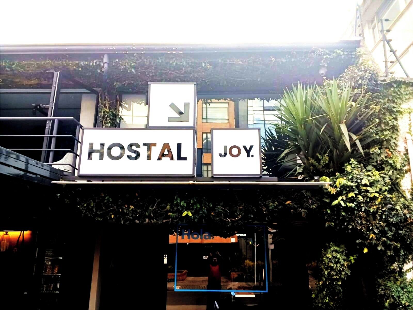 A sign with the words 'HOSTAL' and 'JOY' indicating the name of a hostel.