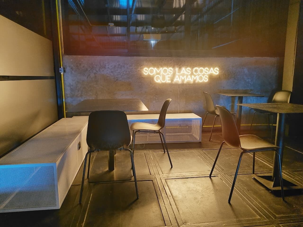 Un interior moderno con un letrero de neón, un sofá, dos sillones y una mesita.