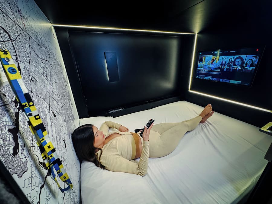 Una habitación con cama, televisión y una pared decorada con un diseño de mapa.