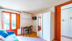 A room with a sofa, a dining table with chairs, a TV, and a wardrobe. - GuestHost - Beautiful studio of 25 square meters located on the first floor of a building without elevator (6 steps to access), can comfortably accommodate up to 2 people.The property is located in the historic center (Restricted Traffic Zone), just outs (Siensa)
