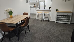 Une cuisine moderne avec des meubles blancs, un îlot central doté de tabourets et un meuble à vin.