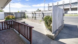 Un espace extérieur clos, doté d’un chemin en béton, d’une clôture en bois et d’une structure métallique en arrière-plan.
