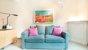 A living room with a light blue sofa, a painting of a town, a cabinet, and a white cabinet. - Casa San Martino in the feel of the middle age (Firenze)