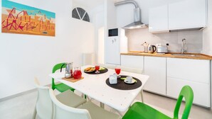 A modern kitchen with white cabinets, a dining table with chairs, and a painting on the wall. - Casa San Martino in the feel of the middle age (Firenze)