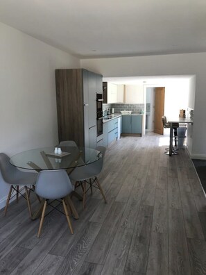 Una cocina moderna con armarios grises, una mesa redonda de cristal y sillas grises.