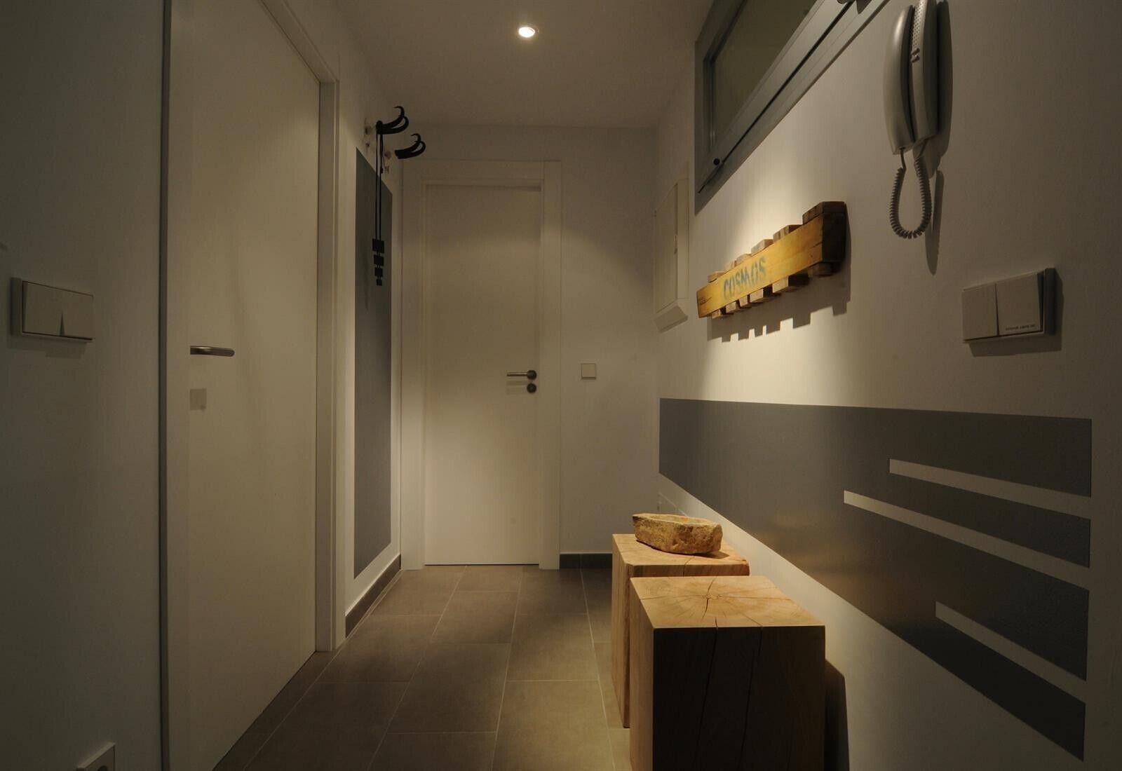 A hallway with a wooden bench, a coat rack, a telephone, and a door.