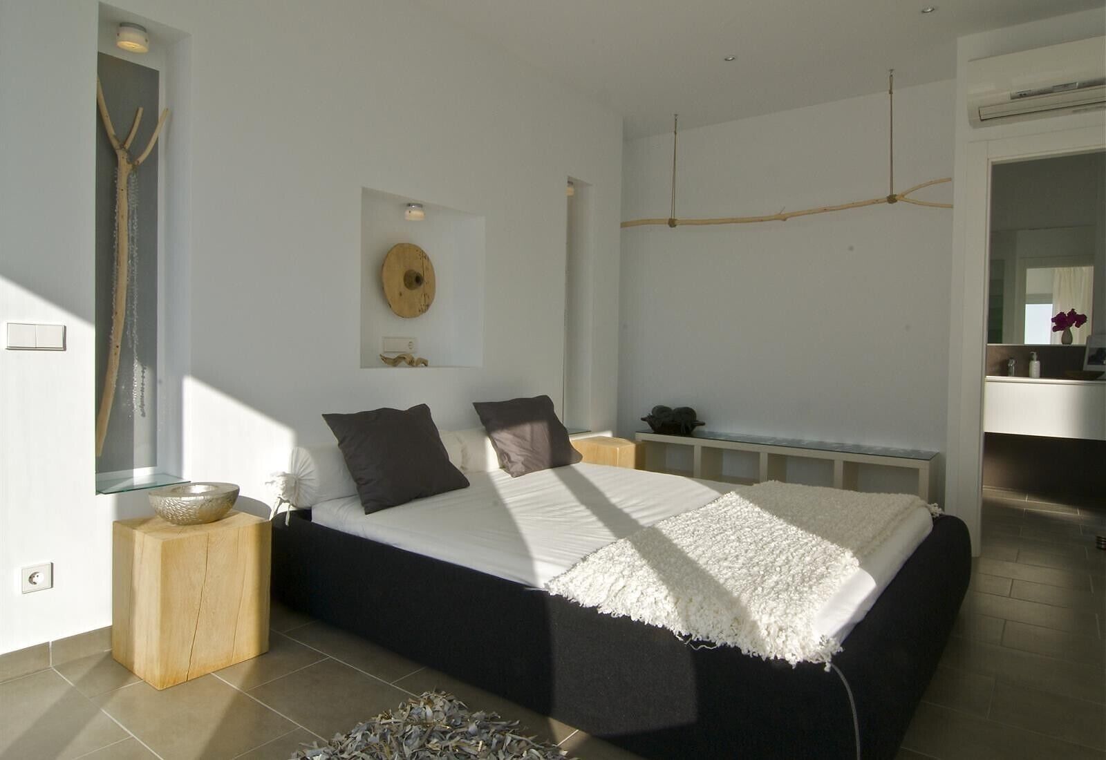 Camera da letto moderna con un letto grande, un comodino in legno, una mensola a parete e una ventola a soffitto.