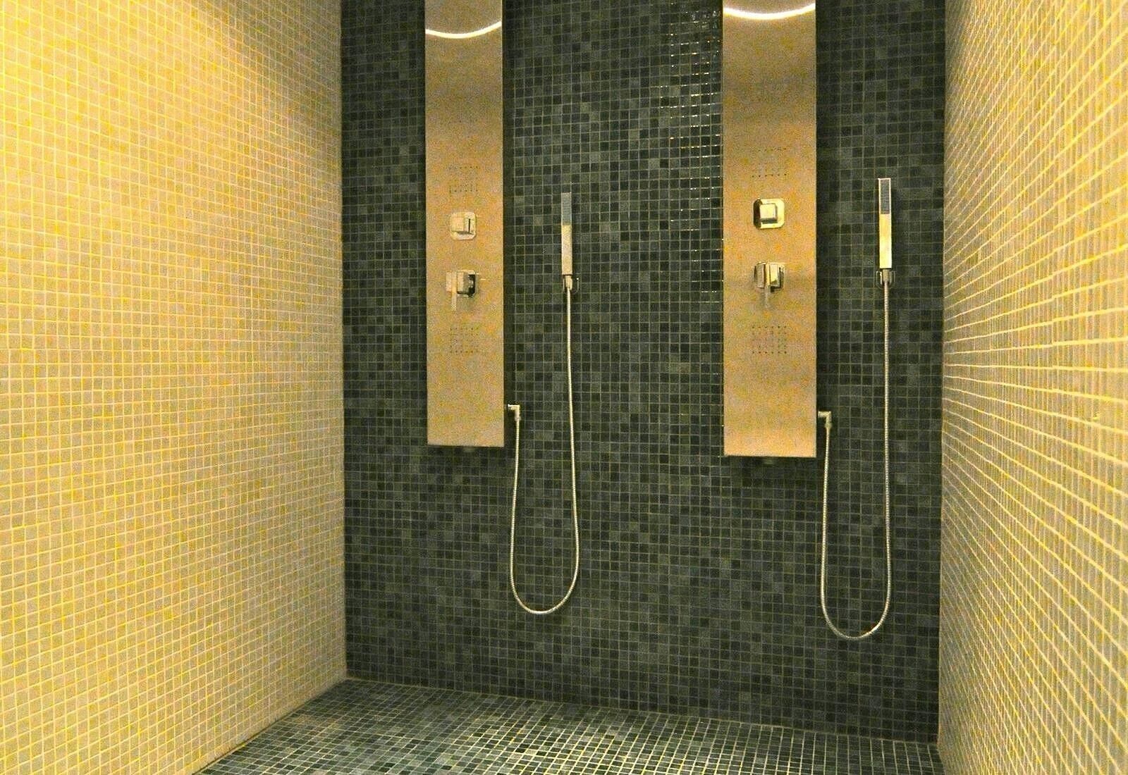 A tiled shower area with two vertical fixtures, likely for hand and body washing.