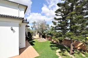 Un edificio bianco con tetto in tegole, un vialetto lastricato e un prato curato.