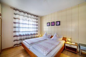 A double bed with a wooden frame, two bedside tables with lamps, a bench, and a window with curtains. - Apartment 'Typ D Haus Pöder' with Mountain View, Shared Garden and Wi-Fi (Naturno)