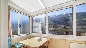 A room with a table and bench, large windows with a mountain view, and a lamp on the table. - Studio Apartment 'Apartment Typ C Haus Pöder' with Mountain View (Naturno)