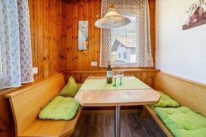 A corner room with wooden walls, a table with two green cushioned benches, a bottle of wine, and a lamp. - Apartment 'Typ B Haus Pöder' with Mountain View, Shared Garden and Wi-Fi (Naturno)