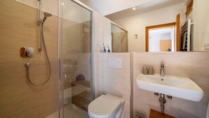 A modern bathroom with a glass-enclosed shower, a white toilet, and a sink with a mirror above it. - Apartment 'Typ B Haus Pöder' with Mountain View, Shared Garden and Wi-Fi (Naturno)