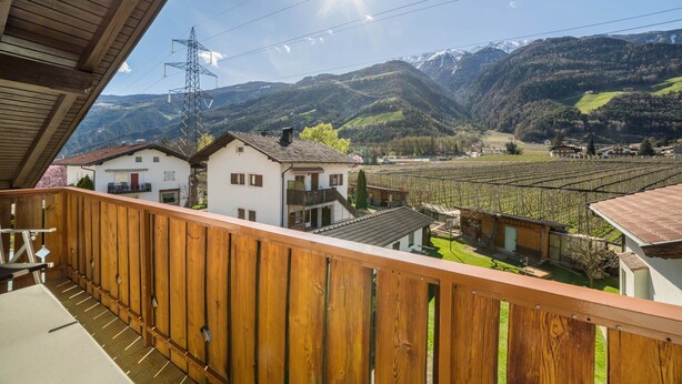 A balcony with a wooden railing overlooking a mountainous landscape with houses and vineyards. - Apartment 'Typ A Pöder's Haus' with Mountain View, Shared Garden and Wi-Fi (Naturno)