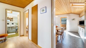 A modern interior with a wooden ceiling, a dining area with chairs and a table, and a kitchen with cabinets and a TV. - Apartment 'Typ A Pöder's Haus' with Mountain View, Shared Garden and Wi-Fi (Naturno)
