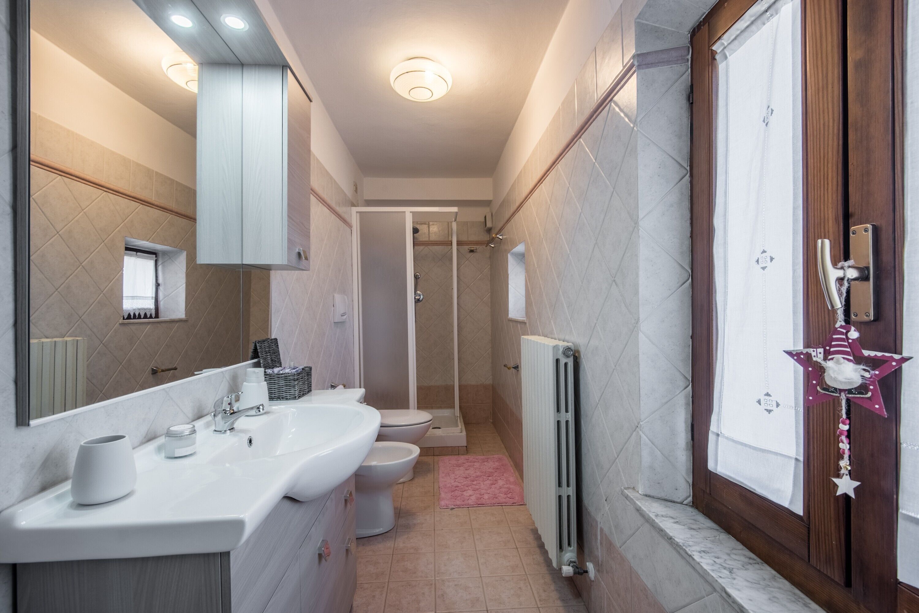 A modern bathroom with a large mirror, two sinks, a toilet, and a shower area.