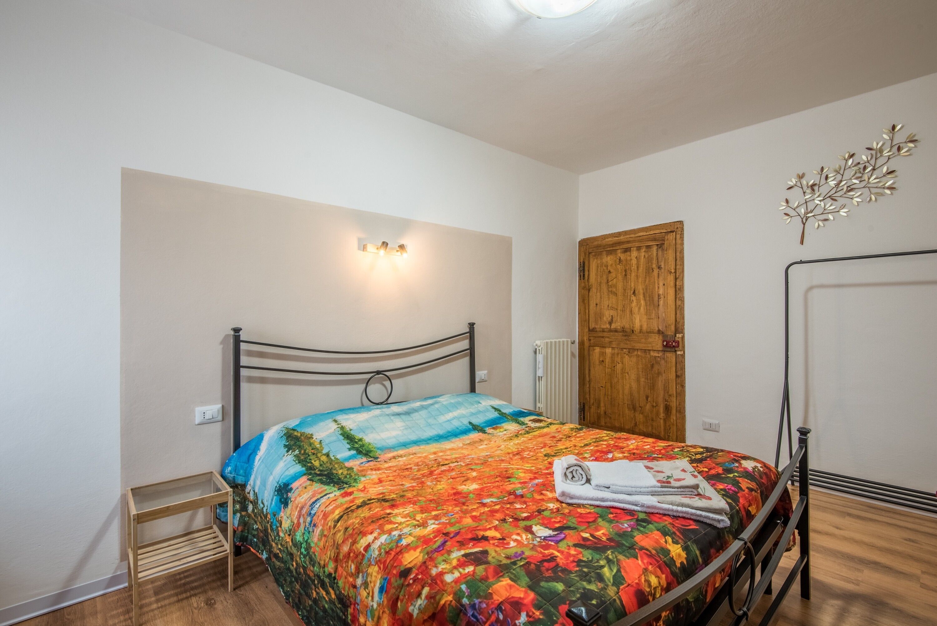A bedroom with a bed, a wooden door, a radiator, and a wall-mounted light fixture.