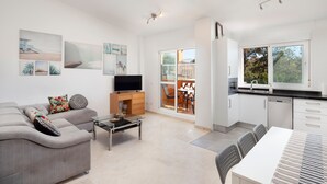Un salon moderne avec un canapé, un téléviseur et un coin repas.