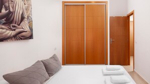 Une chambre à coucher avec un lit, des oreillers, une armoire en bois et un tableau accroché au mur.