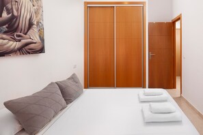 Un dormitorio con cama, almohadas, un armario de madera y un cuadro en la pared.